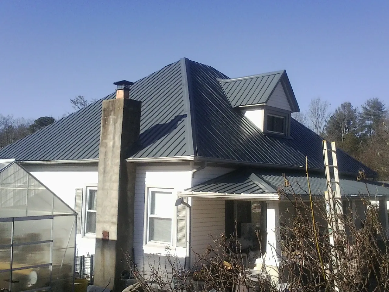Dark blue standing seam metal roof on a white farmhouse with dormer — Slate & Tile Roof Repair by Roofing Brothers in Abingdon