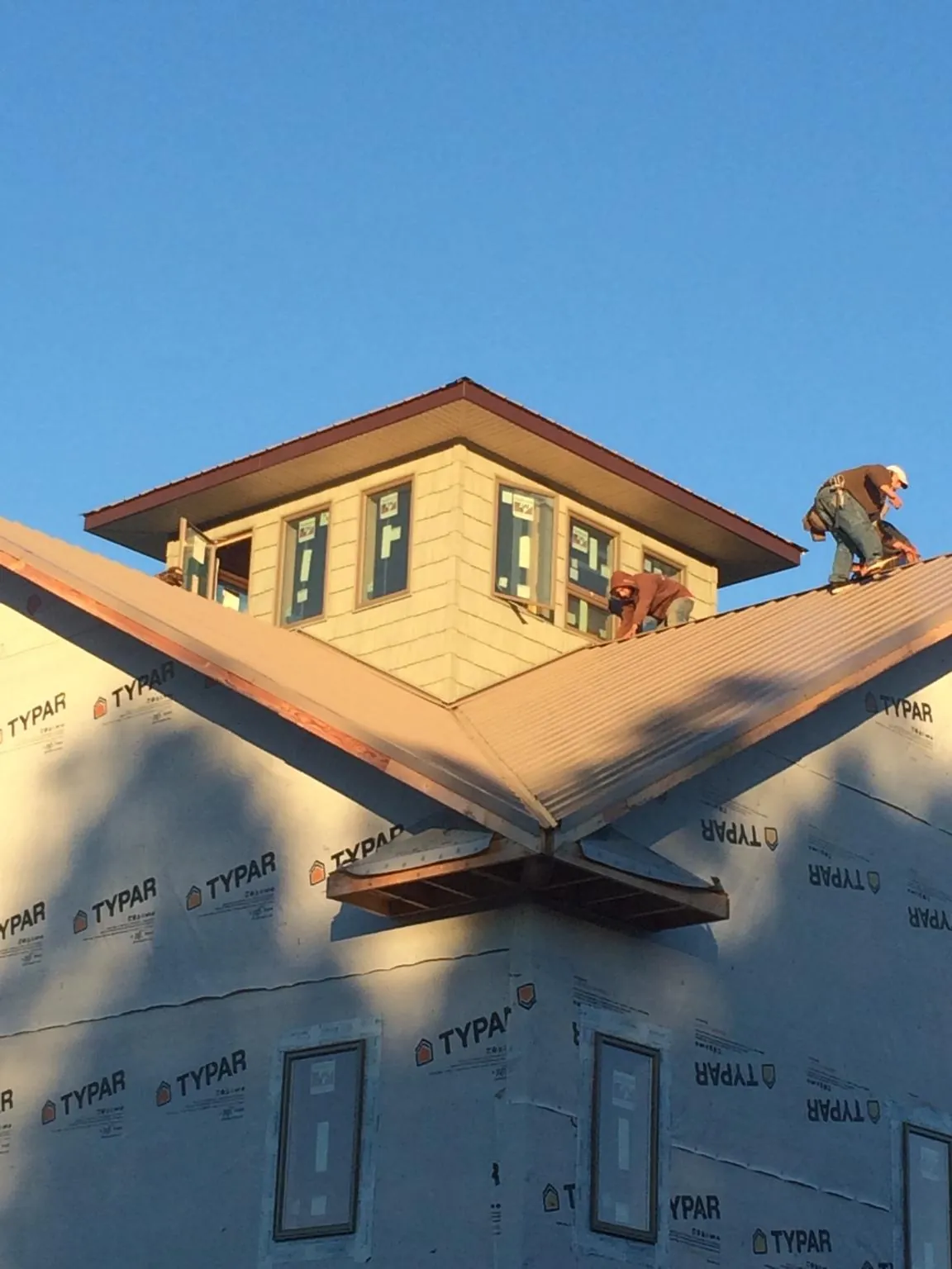 Roofers working around a rooftop cupola on a new metal roof at sunset — Roof Waterproofing in Abingdon by Roofing Brothers